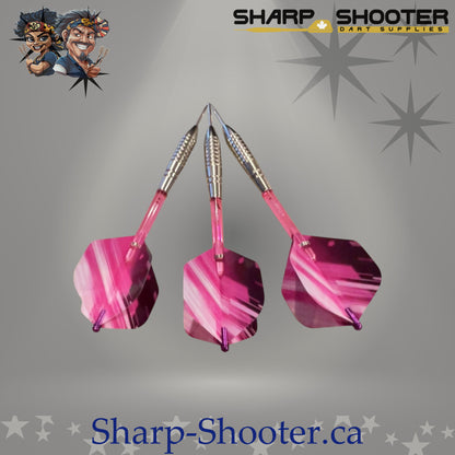 Pink Lady steel dart set featuring silver stainless The Warden barrels, pink flights, matching plastic shafts with aluminum shaft rings, and steel tips arranged on a neutral grey studio background.